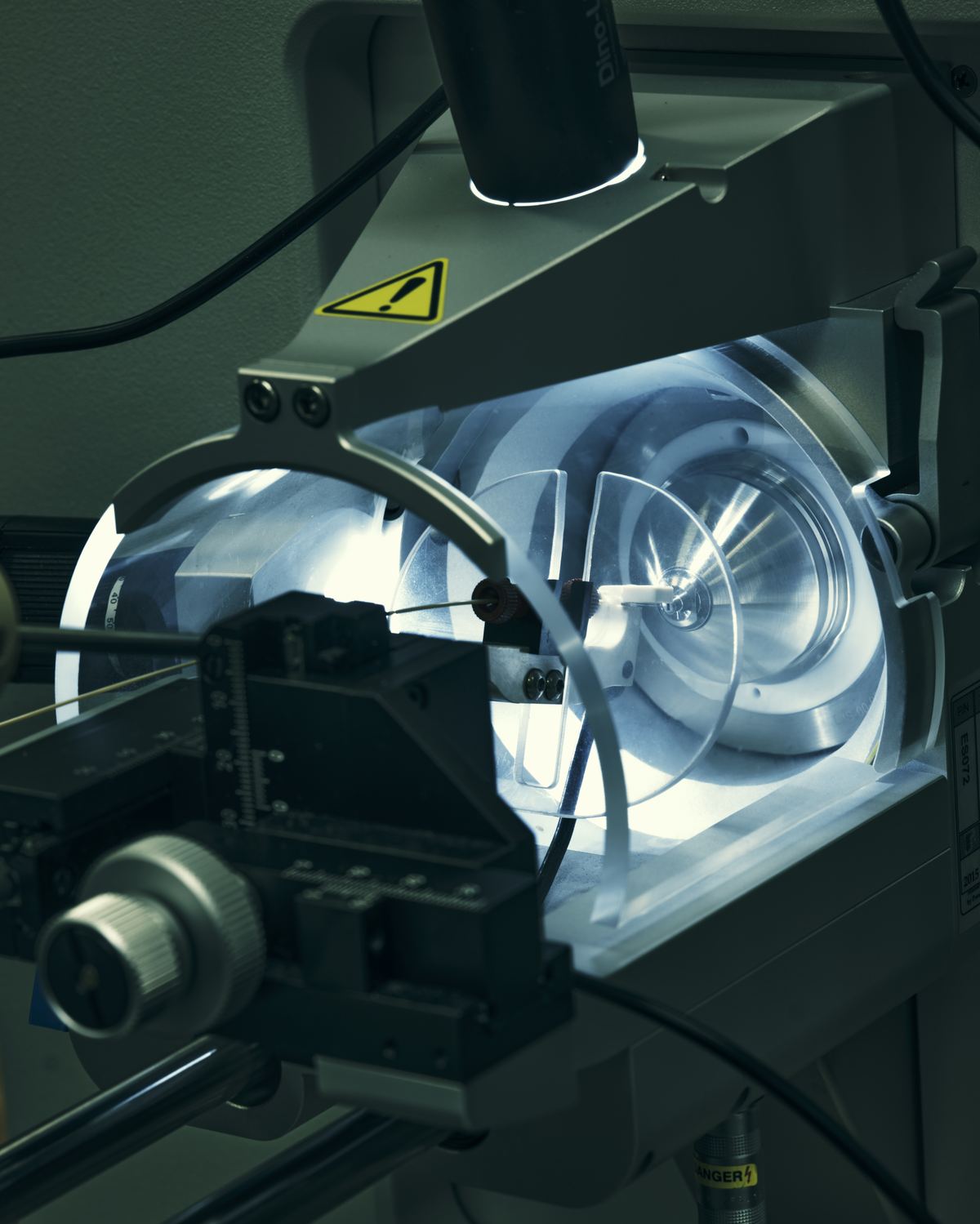Close-up of a mass spectrometer ion source inlet, illuminated during operation